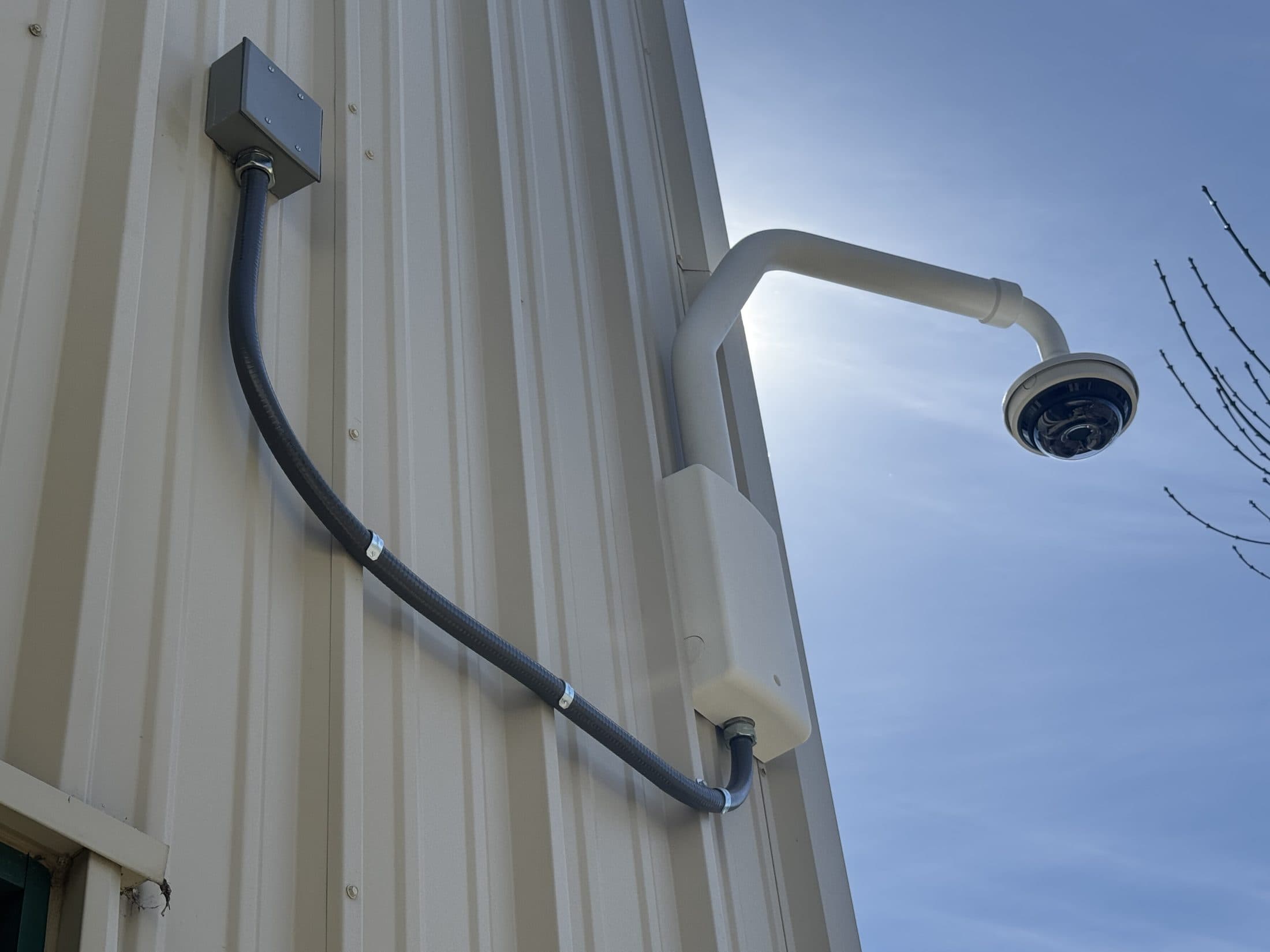 Exterior commercial security camera mounted with conduit on a metal building