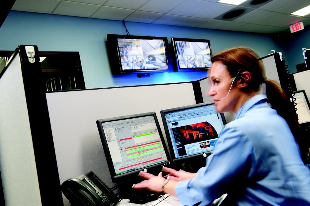 Central station operator wearing a headset at an alarm monitoring workstation