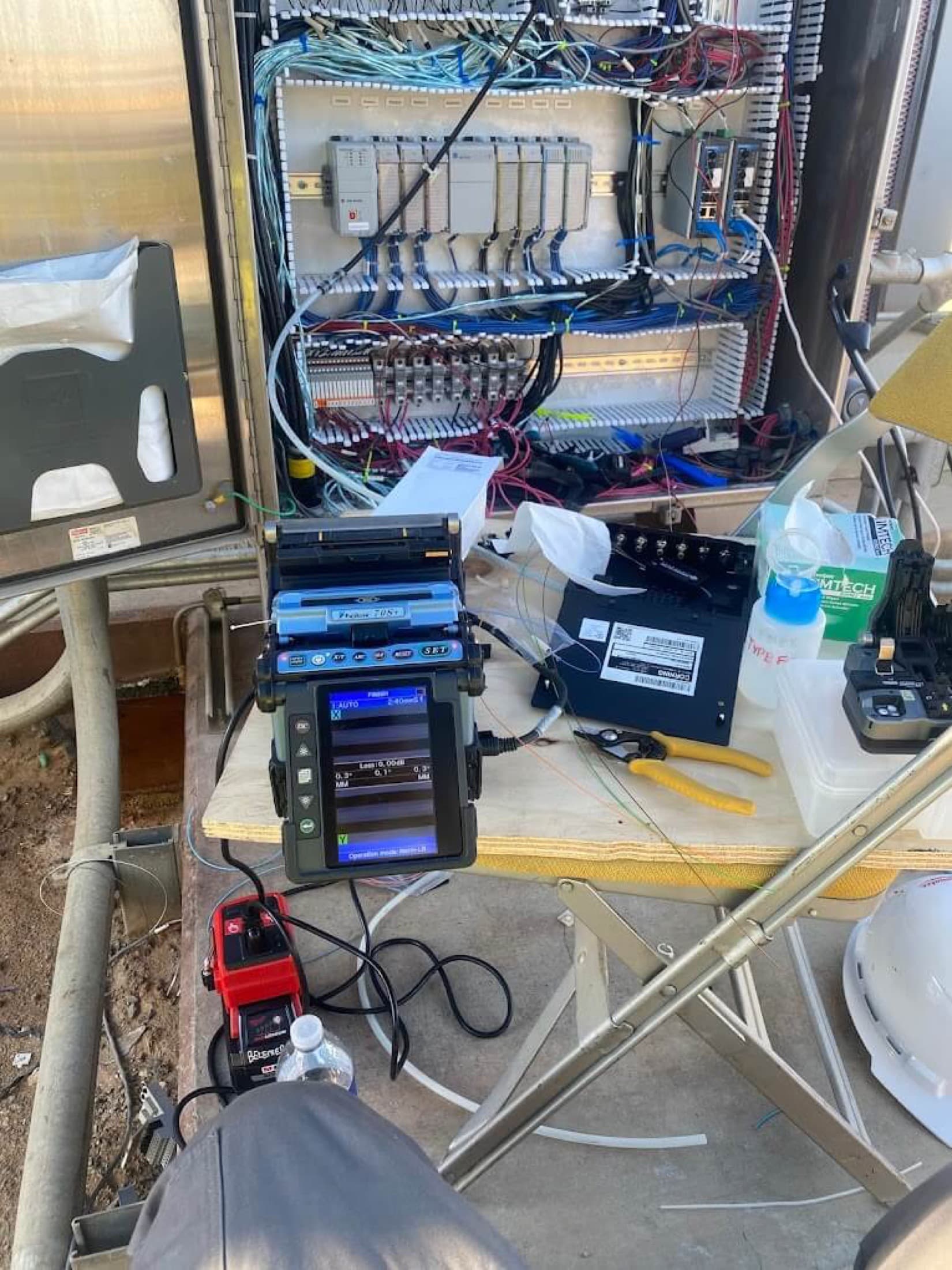 Fiber splicing equipment beside an open commercial control cabinet