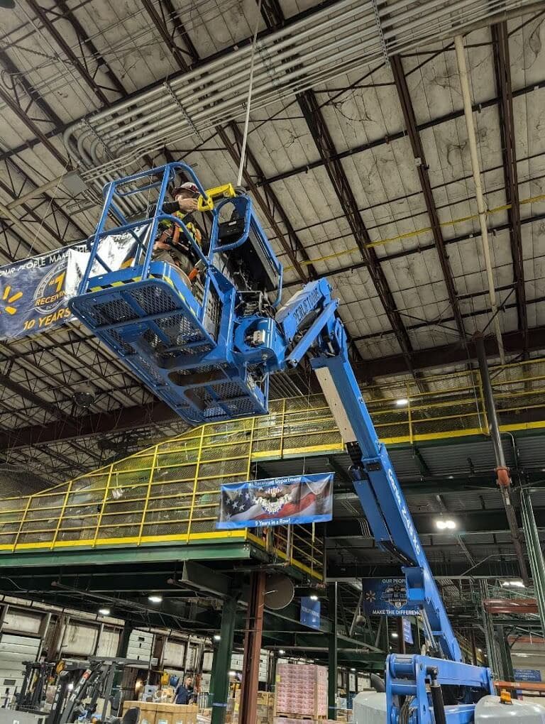 Commercial security camera installation from a lift inside an active warehouse