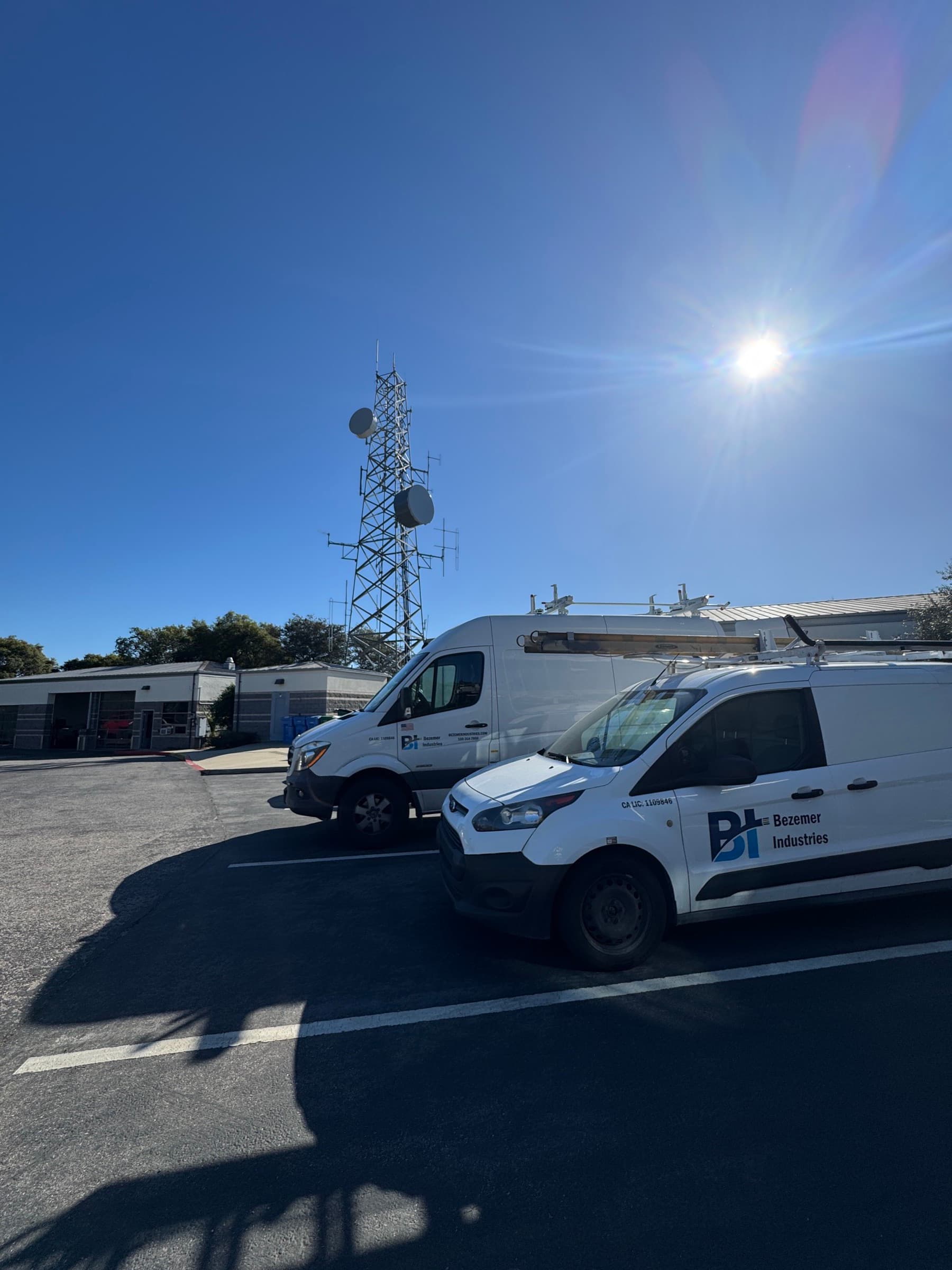 Bezemer Industries service vans parked near a communications tower