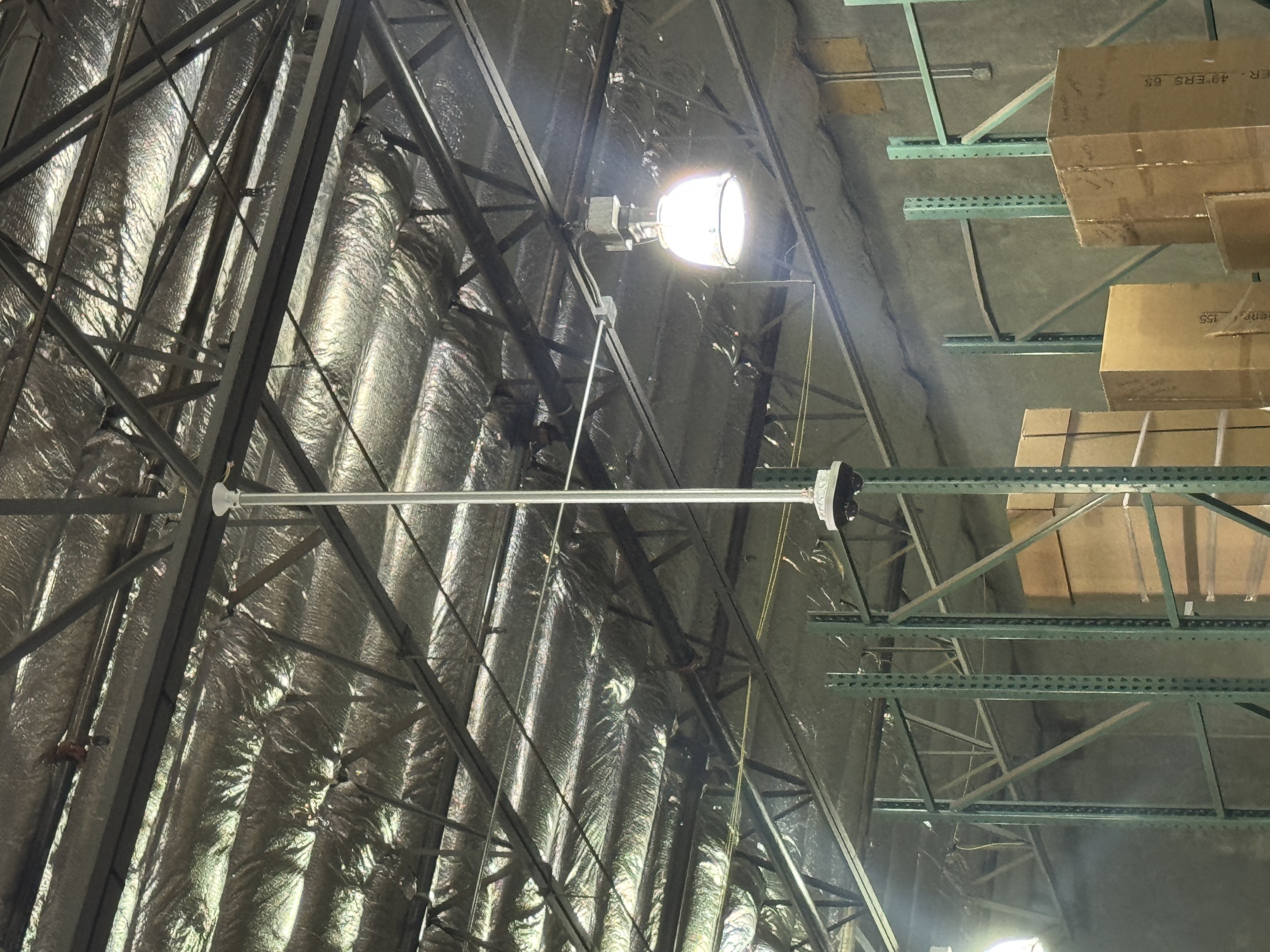 Commercial warehouse low-voltage device mounted near exposed ceiling structure