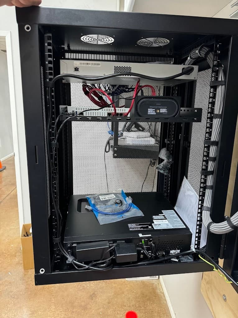 Wall-mounted network cabinet from Bezemer's project photos, with rack equipment, network connections, cable management, and backup power