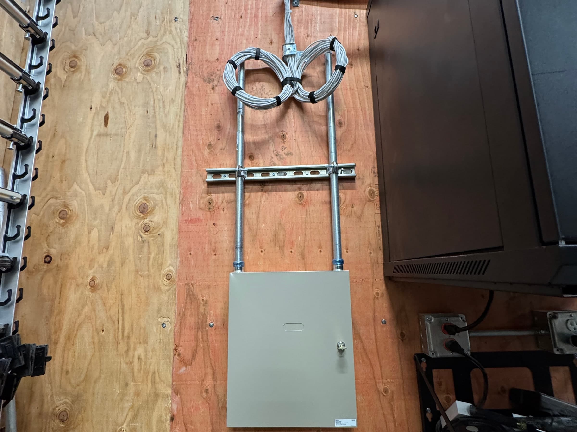 Wall-mounted structured cabling enclosure with conduit and bundled cable loops