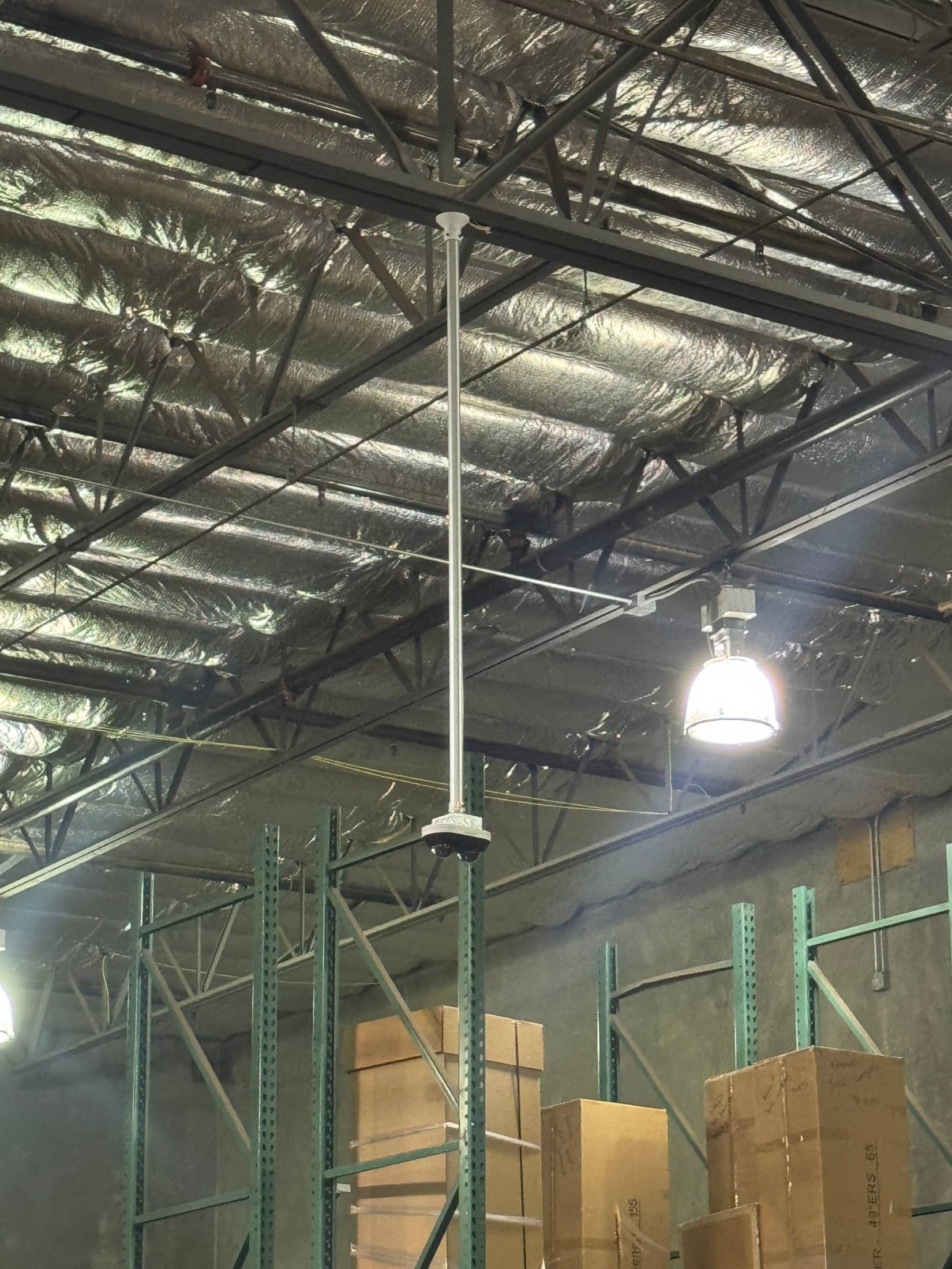 Commercial warehouse low-voltage device mounted near exposed ceiling structure