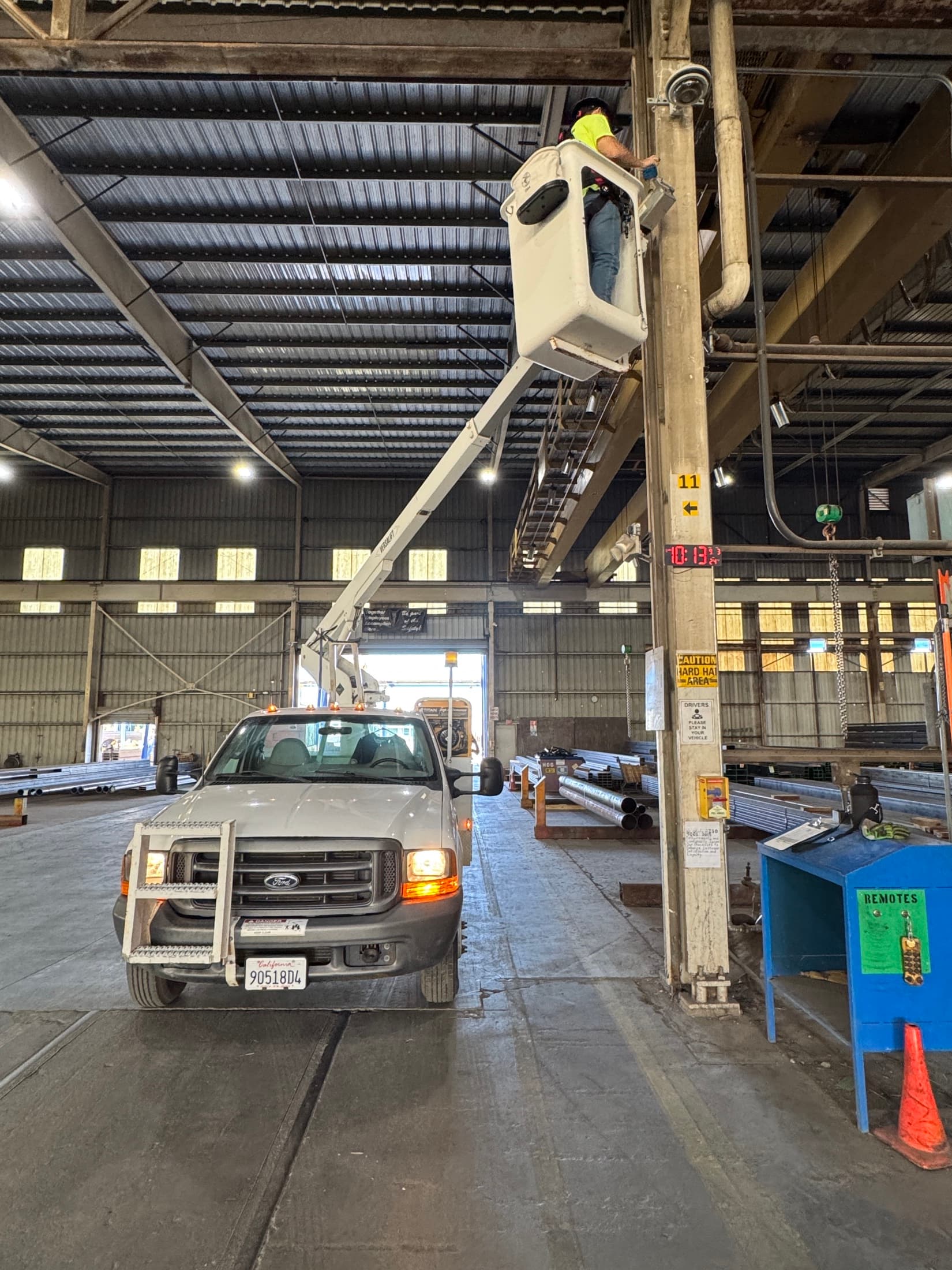 Technician in a bucket lift working above an active commercial warehouse floor